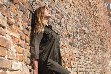 Beautiful young woman posing against stone wall of antic castle. Woman posing against the backdrop of medieval ruins