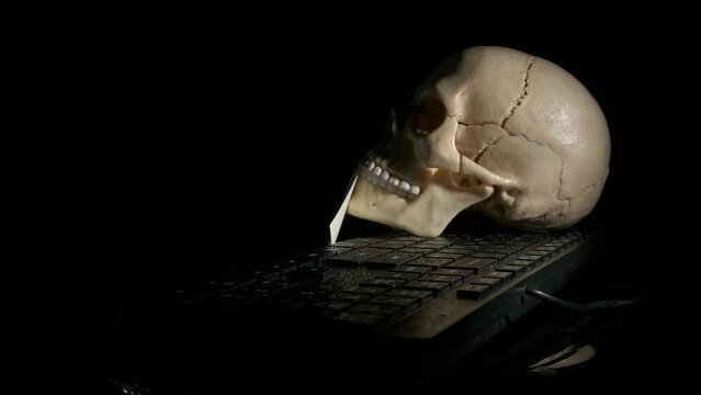 Password on paper to hack by skull. A view of password on paper in human skull mouth on the computer against black background.