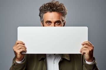 Portrait of a man holding a white horizontal sheet of paper with a place for writing and mockup. - obrazy, fototapety, plakaty