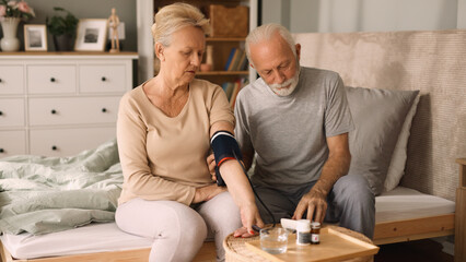 Senior couple measuring blood pressure at home