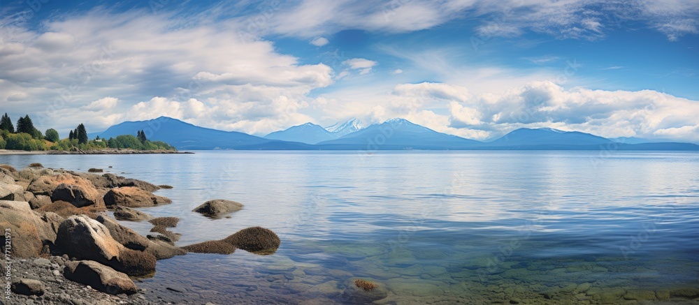 Poster Scenic view of mountains and a body of water with rocks in the foreground, creating a tranquil and picturesque landscape