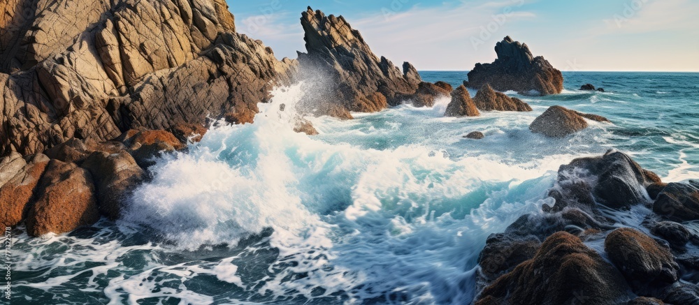 Poster powerful waves collide with rugged rocks along the sandy shore creating a mesmerizing display of nat