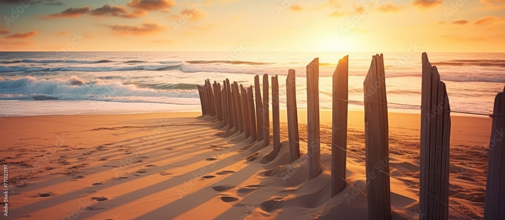 Poster a rustic wooden fence stands along the sandy beach, while ocean waves crash in the background under 
