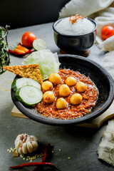 Hot plate egg or Sambal Gami Telur is Traditional food from Indonesia. Served on plate with a bowl of rice and vegetables top view. Super hot and spicy food