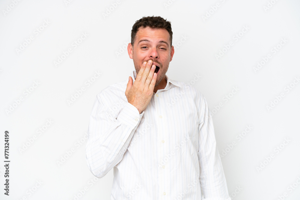 Wall mural young caucasian handsome man isolated on white background yawning and covering wide open mouth with 