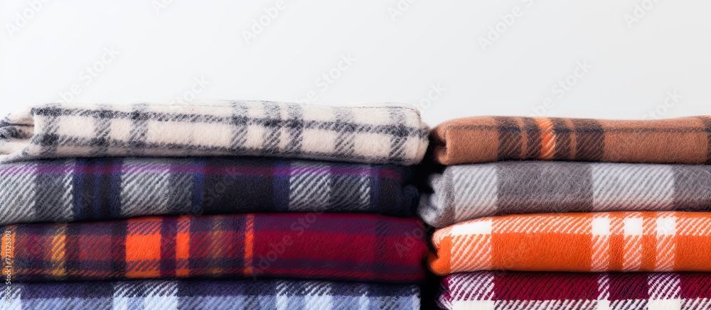 Poster Several blankets neatly piled on a table, showcasing different textures and colors, creating a cozy atmosphere