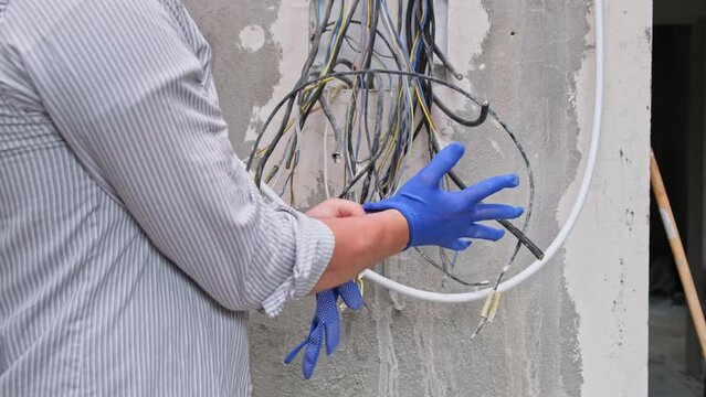 Close up view of electrician wearing gloves before work on panel cable 