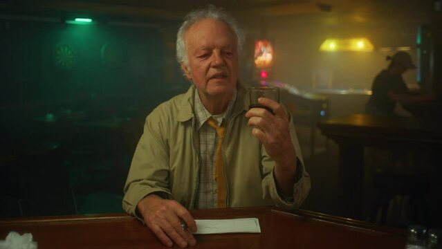 Man drinks at a dingy bar alone.