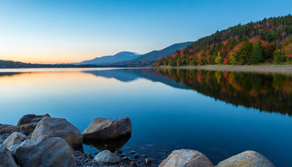 Obraz premium Serene lake, its colors reflecting off the tranquil waters, illuminating the scattered stones