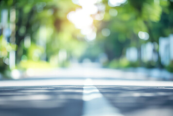 Blurred background of an outdoor scene with white and green colors, blurred focus on a road in the foreground. The blurry urban landscape is adorned with lush trees. - obrazy, fototapety, plakaty