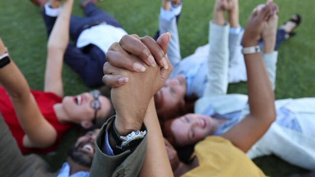 A group of joyful colleagues celebrate teamwork with a hands-on moment in the park. Joyful Team Bonding Moment in Grass Field