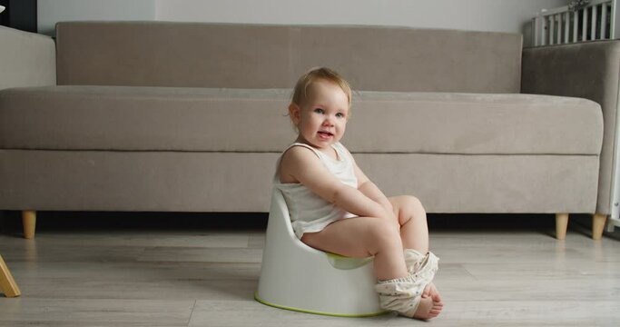 Side view of adorable smiling girls sitting on chamber pot,potty training hygiene. child learning sit on toilet wc seat at home. Kid about two years old. High quality 4k footage