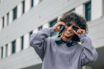 young afro hair man with headphones and phone on the street