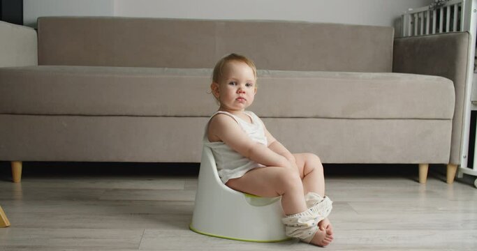 Side view of adorable smiling girls sitting on chamber pot,potty training hygiene. child learning sit on toilet wc seat at home. Kid about two years old. High quality 4k footage