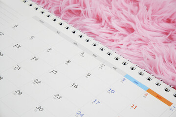 Calendar on pink fur background close up.