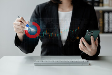 A woman is drawing a red circle on a computer screen. She is holding a pen and a cell phone. Concept of technology and creativity, as the woman is using both the pen