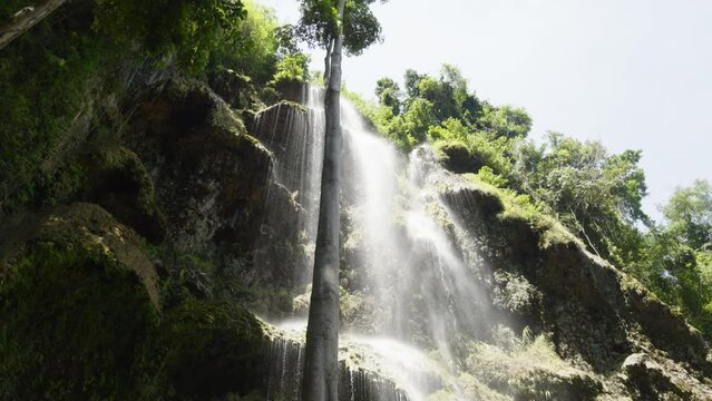 Tumalog waterfall close up with water falling down the rocky cliffside of the waterfall in Cebu, Philippines.