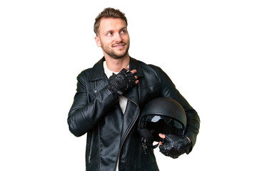 Young caucasian man with a motorcycle helmet over isolated chroma key background looking up while...