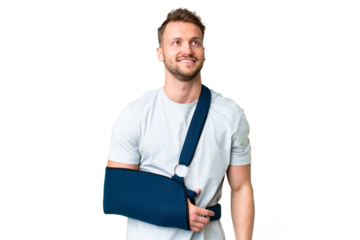 Young caucasian man with broken arm and wearing a sling over isolated chroma key background thinking an idea while looking up