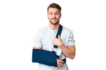 Young caucasian man with broken arm and wearing a sling over isolated chroma key background with surprise facial expression - obrazy, fototapety, plakaty