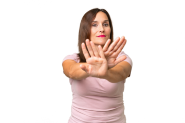 Middle-aged caucasian woman over isolated background making stop gesture with her hand to stop an act