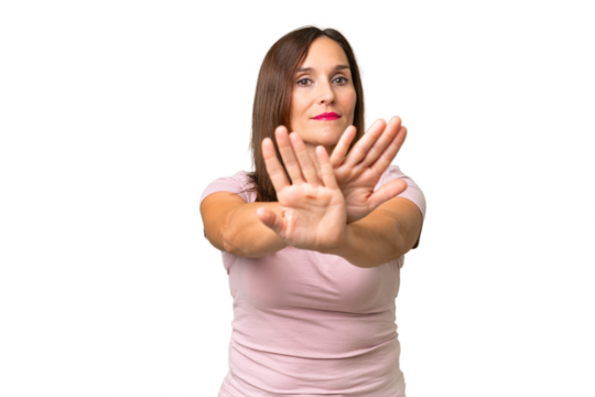 Middle-aged caucasian woman over isolated background making stop gesture with her hand to stop an act