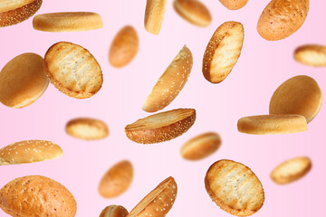 Fresh burger buns falling on pink background