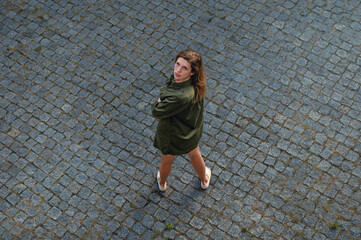 View from above of young woman looks up. Beautiful woman posing while standing outdoor.