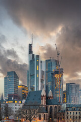 Sunrise on a river bank in the middle of a big city. Spring with a view of the skyline of the financial district and the historic buildings of Frankfurt, Hesse - obrazy, fototapety, plakaty