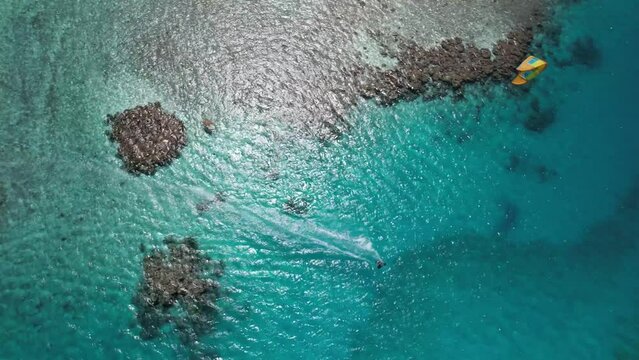 A kite surfer gliding over turquoise waters at los roques, aerial view