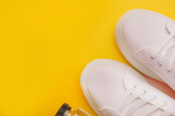 Sneakers and bottle of water on yellow background. Concept of healthy lifestyle.