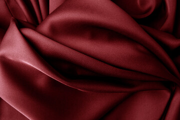 Red silk silky satin fabric. Wavy shiny luxurious shine drapery background, material texture. Full...