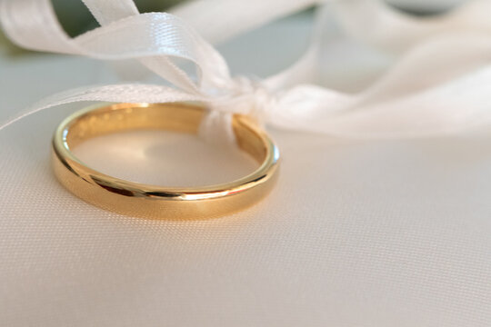 golden wedding ring tied with elegant white ribbon