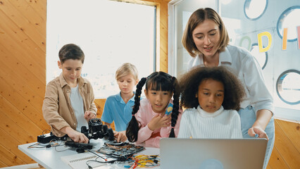 Caucasian teacher praise student while looking at learner work or presentation. Group of diverse student looking at presentation and fixing motherboard at table with chips and wires placed. Erudition. - obrazy, fototapety, plakaty
