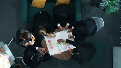 Close up of professional business team hands writing and putting sticky note on scrum task board....