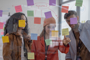 Multicultural startup team collaborate, brainstorm, exchange ideas using sticky notes for solutions