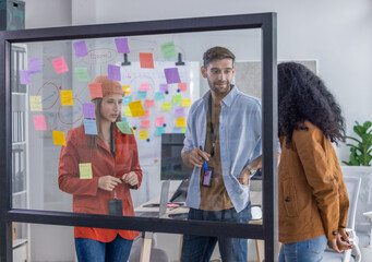 Multicultural startup team collaborate, brainstorm, exchange ideas using sticky notes for solutions