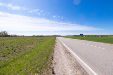 A beautiful springtime scenery with asphalt road in Latvia. Natural landscape of Northern Europe