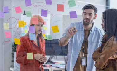 Multicultural startup team collaborate, brainstorm, exchange ideas using sticky notes for solutions