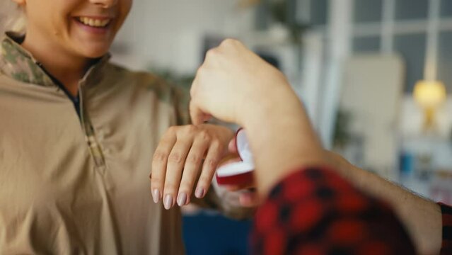 Man proposing to military girlfriend, putting ring on her finger, engagement
