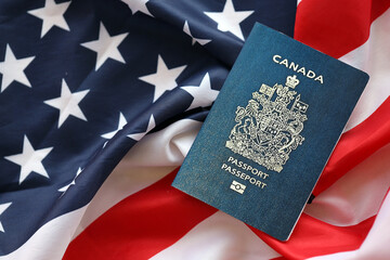 Fototapeta premium Canadian passport on United States national flag background close up. Tourism and diplomacy concept