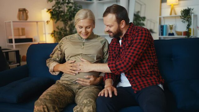 Happy husband touching belly of pregnant military wife, rejoicing paternity