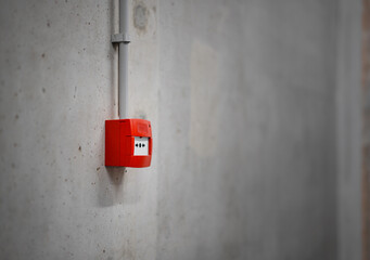 Fire alerm button. Red box on concrete wall.