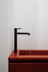 Red countertop with black faucet on a bathroom sink
