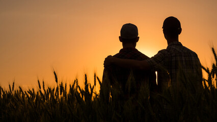 A couple of young men hugging tenderly and looking at the sunset