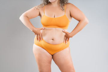 Fat woman in orange underwear on gray background, obesity and cellulite, overweight female body, weight loss concept - 771413769