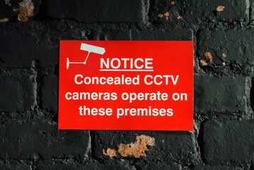 Close Up of Small Red Notice on Old Brick Wall  'Notice Concealed CCTV cameras operate on these premises' 