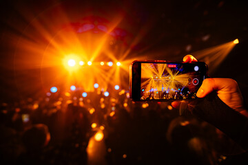 Hands holding phone and making photos on the concert