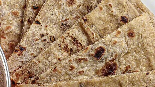 Handmade flat bread chapati and dal tadka fry in brass bowl pan on white plate rustic wooden background pan over top view zoom out