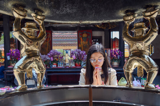 Asian female tourists pray at Longshan Temple, famous for its sacredness and landmark Ximending. Longshan Temple, a popular tourist attraction in Taipei, Taiwan.